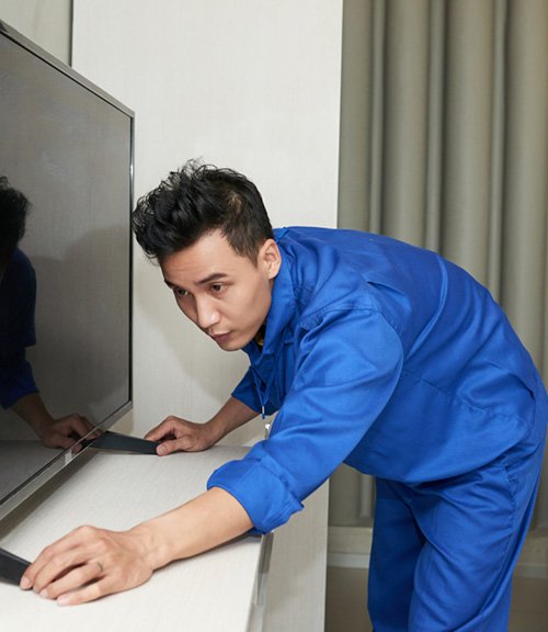 A person carefully checking a flat-screen television during setup