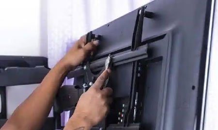 Attaching the mounting bracket arms to the back of a television
